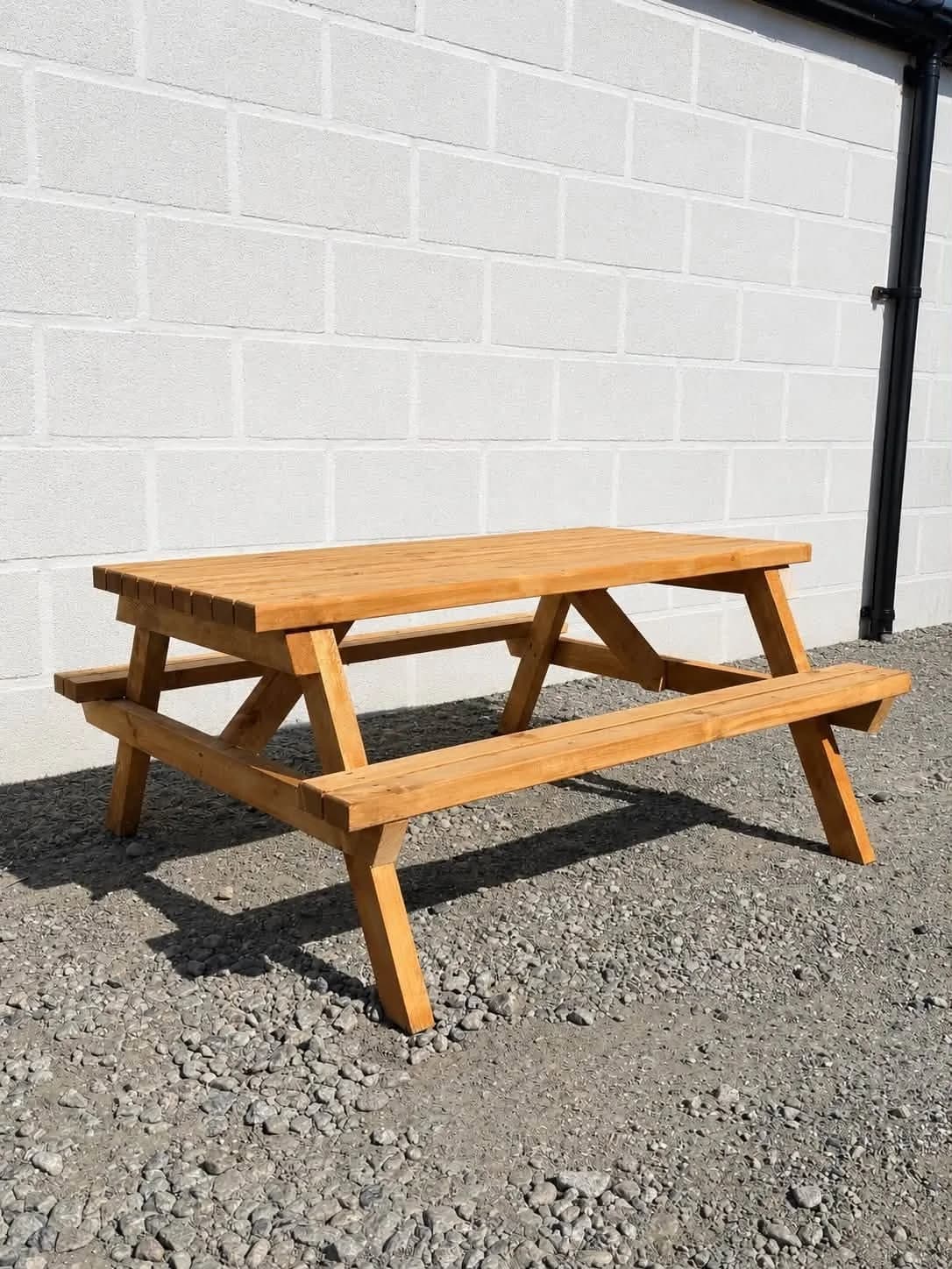 Small timber picnic table with attached benches beside a white wall