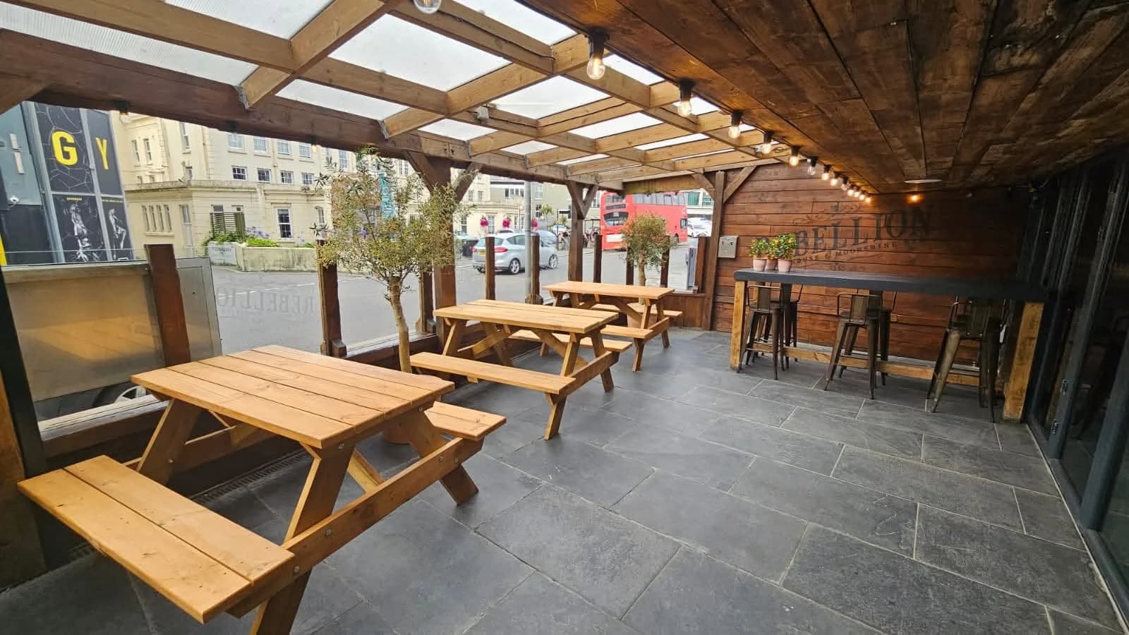 Timber picnic tables arranged beneath a covered commercial outdoor seating area