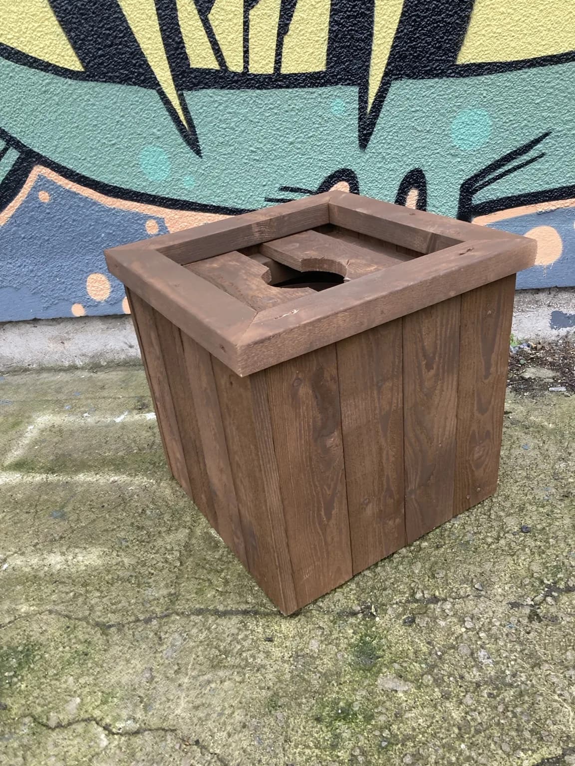 Brown timber Christmas tree stand with square sides and a central opening in the top