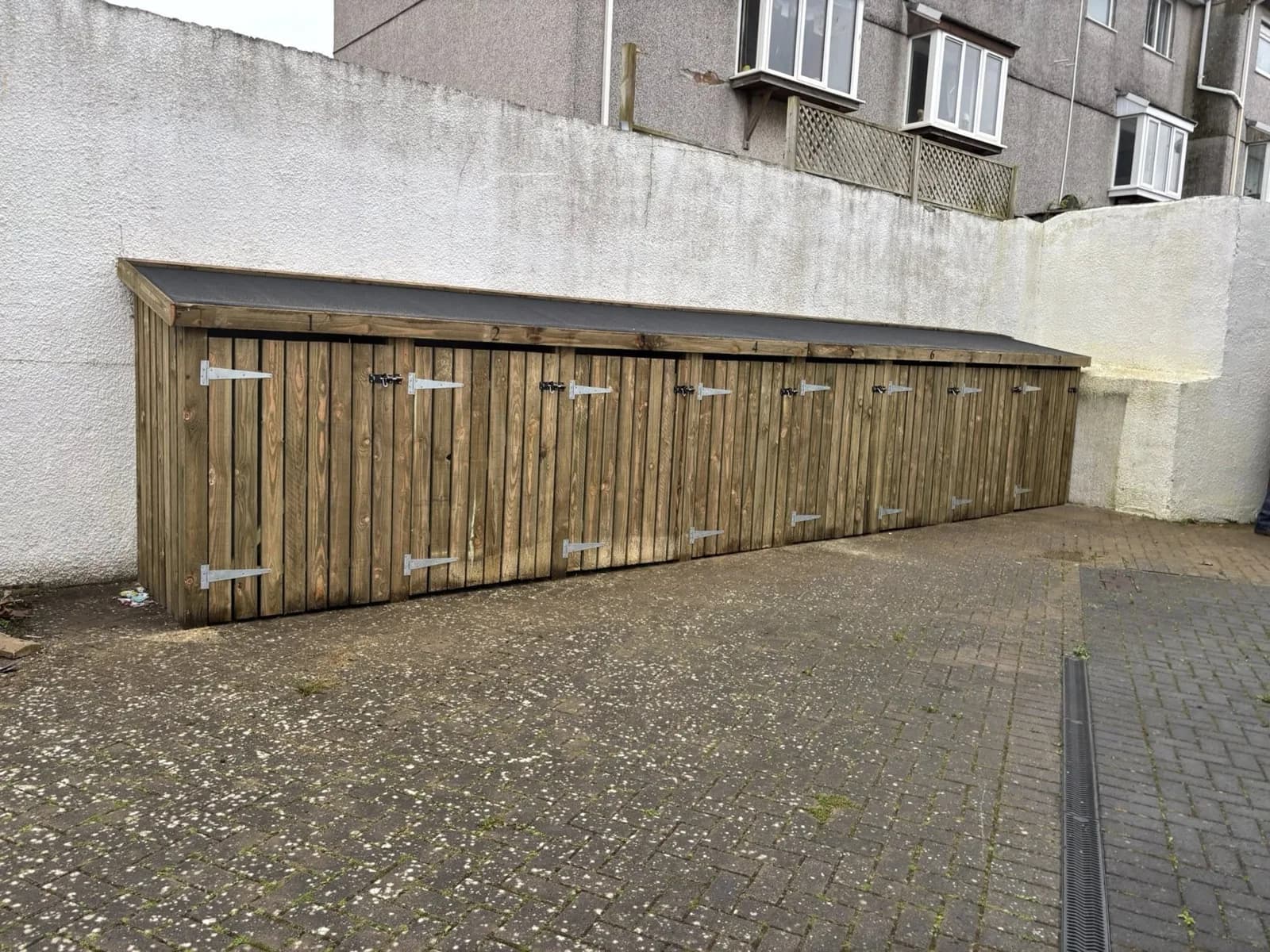 Long timber bin storage enclosure with multiple doors and a sloping roof